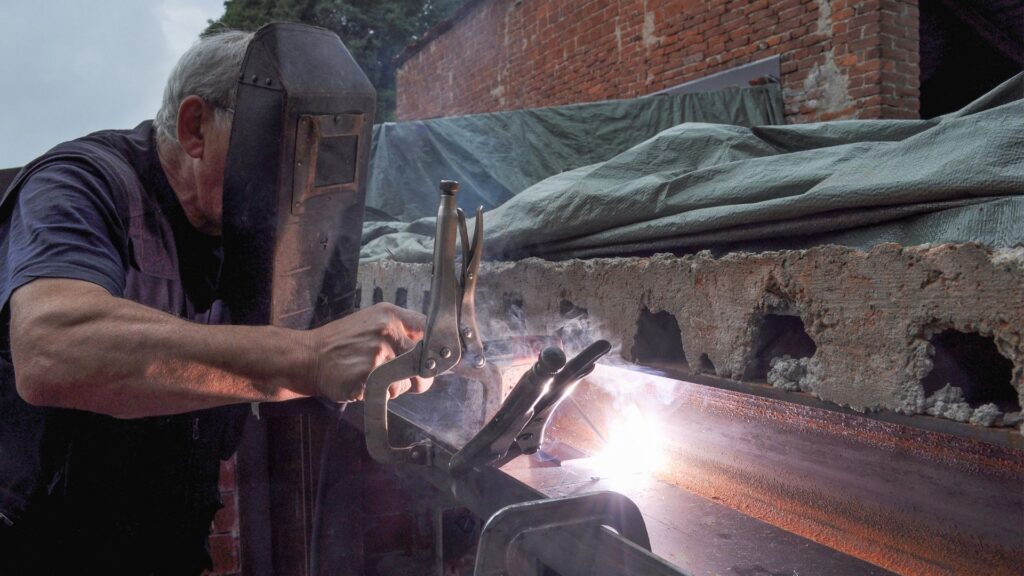 Picture of a man welding, cautious of the welding hazards.